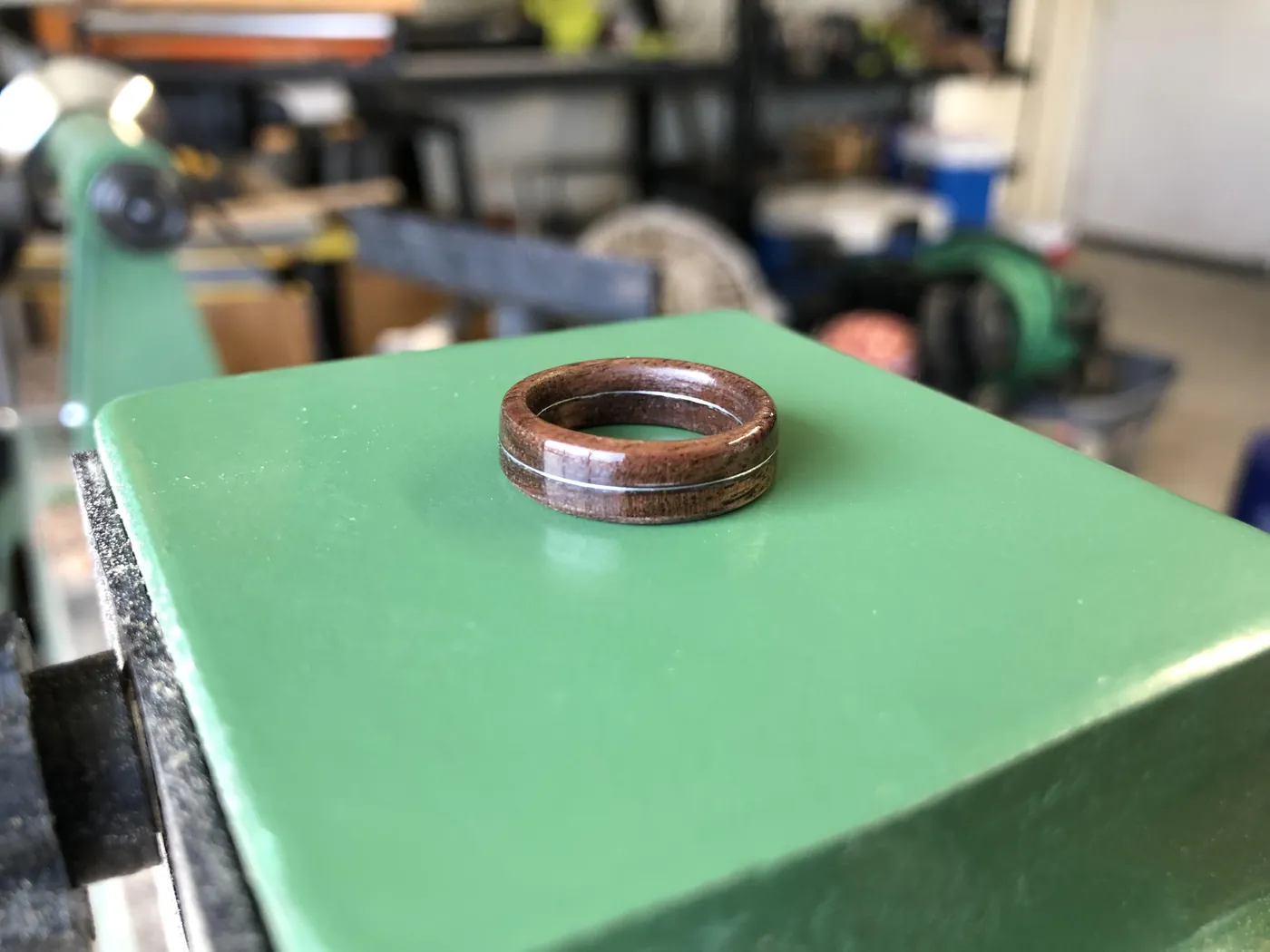 A finished memorial ring resting on the headstock cover of the lathe in the shop