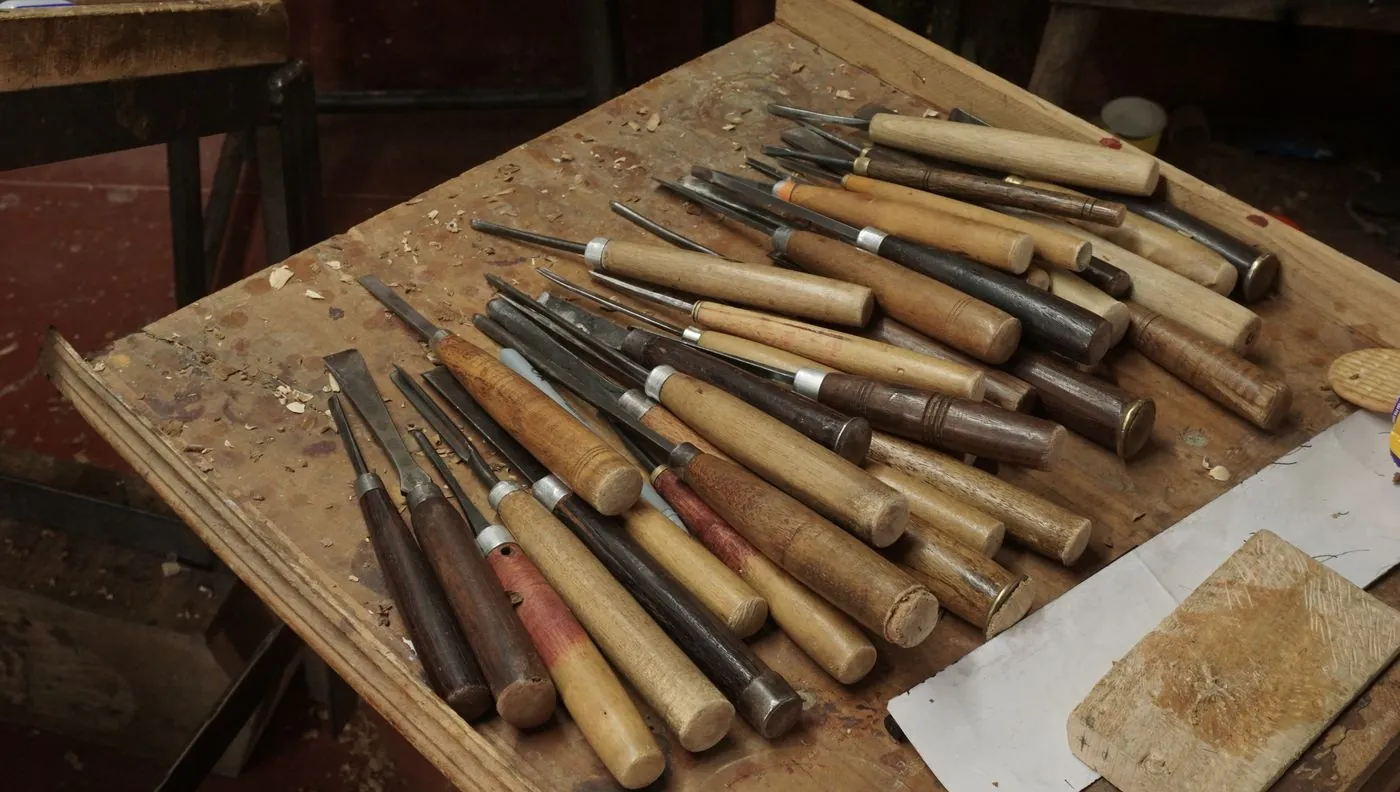 A workbench laid with rows of wooden handled turning tools and chisels